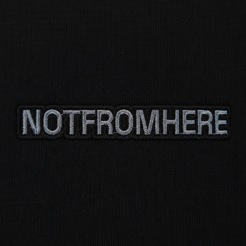 Close-up NOTFROMHERE logo detail on black oversized t-shirt